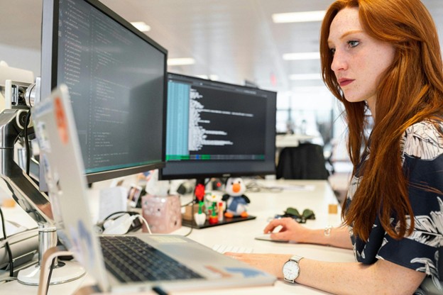 Employee working on multiple computer screens at a digital marketing agency